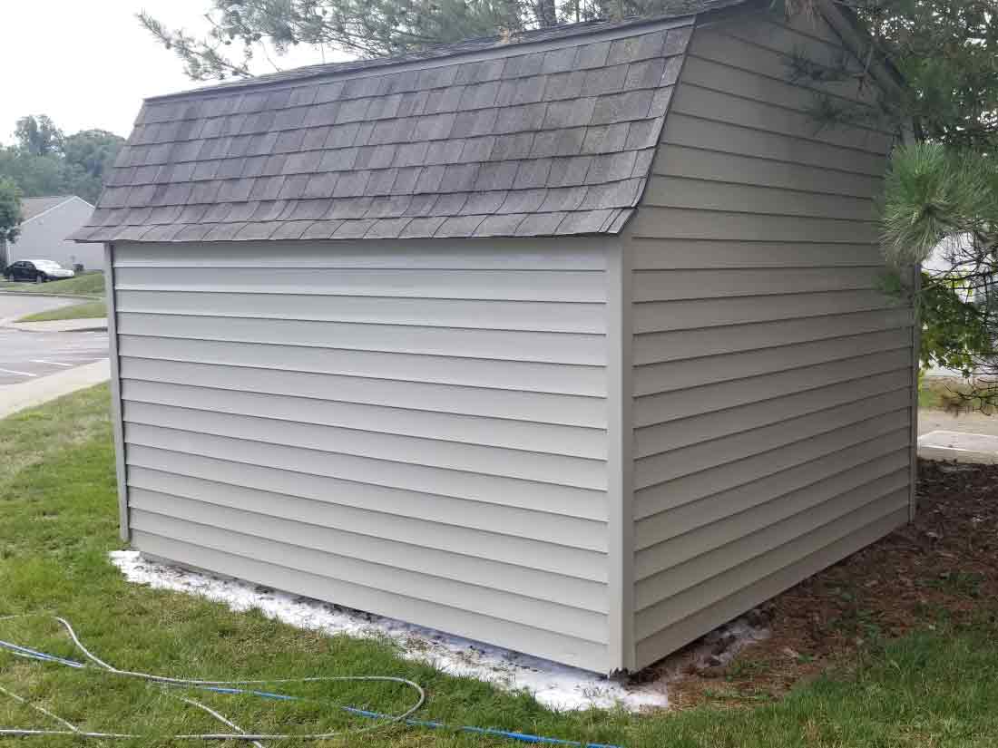 small shed with algae on side after washing